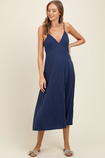 woman wearing a navy blue striped maternity jumpsuit with a v-neckline and flowy skirt style