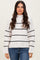 woman wearing a white and black striped oversized sweater with a high neck and long sleeves