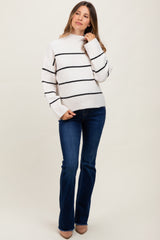 woman wearing a striped maternity sweater with a mock neck and flared jeans, looking stylish and comfortable