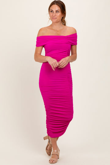 woman wearing a hot pink off-the-shoulder ruched midi dress with a fitted silhouette and heeled sandals