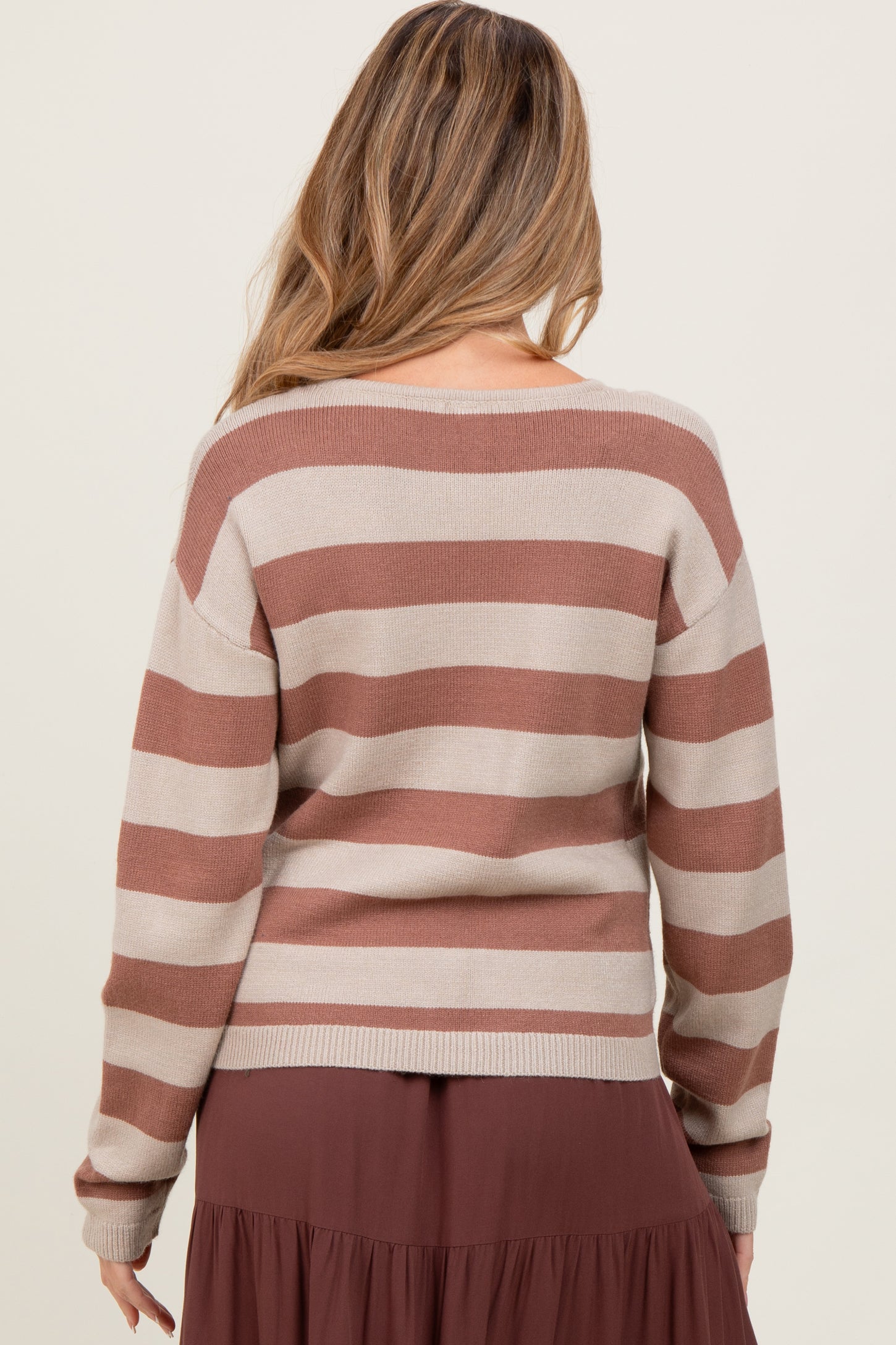 woman wearing a beige and rust striped maternity sweater, viewed from the back