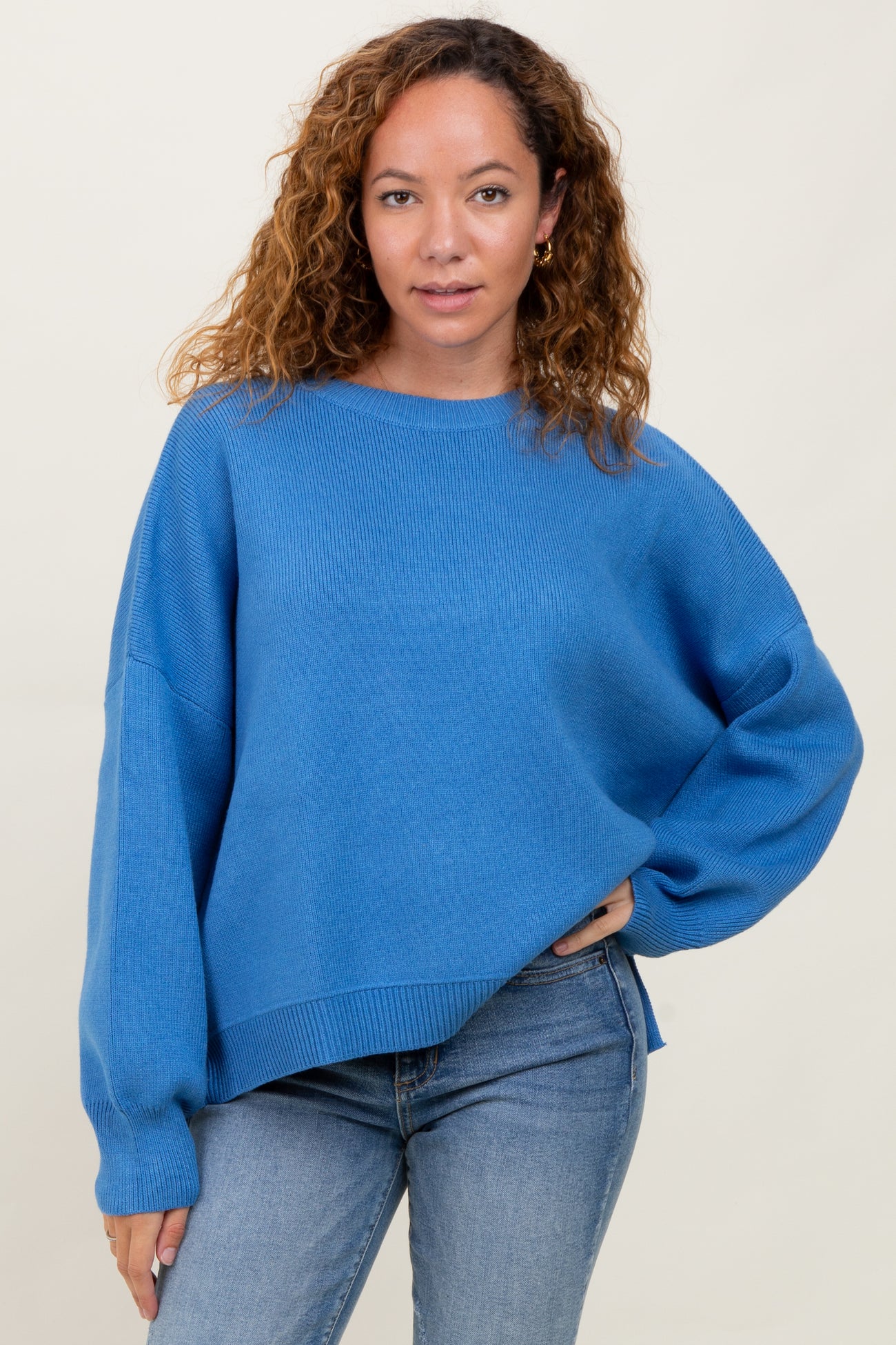 woman wearing a bright blue oversized knit sweater with long sleeves and a relaxed fit paired with light blue jeans