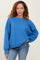 woman wearing a bright blue oversized knit sweater with long sleeves and a relaxed fit paired with light blue jeans