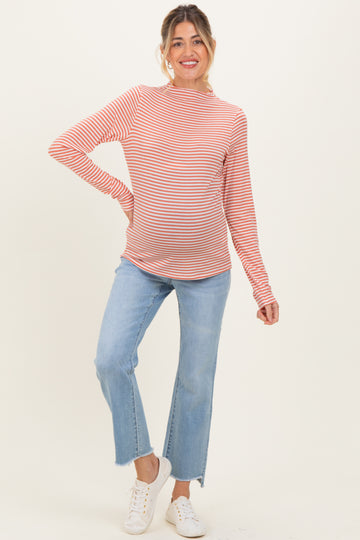 woman wearing a red and white striped maternity top and blue flared jeans with a visible baby bump