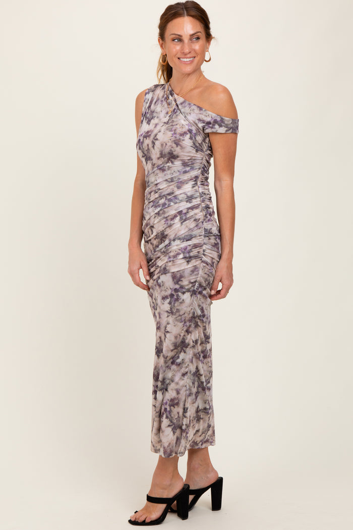 woman wearing a one-shoulder midi dress in a purple and gray tie-dye pattern, styled with black heeled sandals