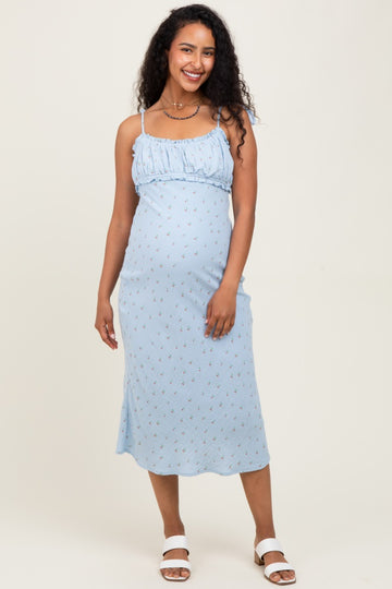 woman wearing a light blue maternity dress with floral print and spaghetti straps, showing her baby bump