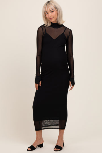 woman wearing a black maternity dress with sheer long sleeves and a fitted silhouette, showing her baby bump