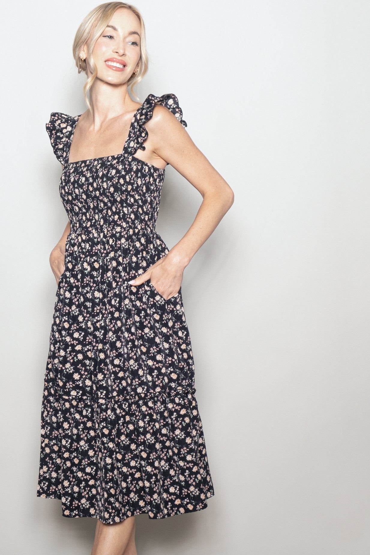 woman wearing a navy floral print midi dress with ruffle straps and pockets
