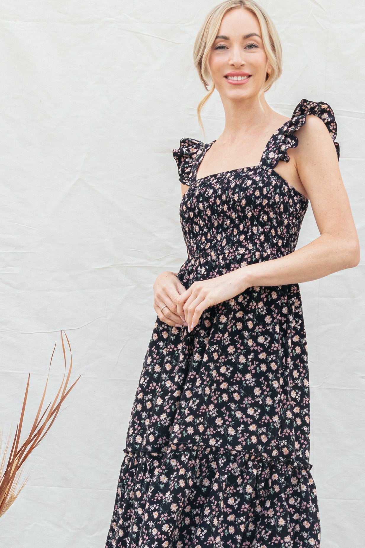 woman wearing a black floral print sundress with ruffle straps and a tiered skirt