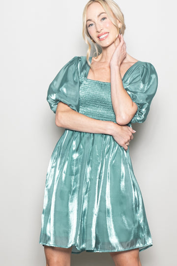 woman wearing a teal puff sleeve mini dress with a smocked bodice and a shiny finish