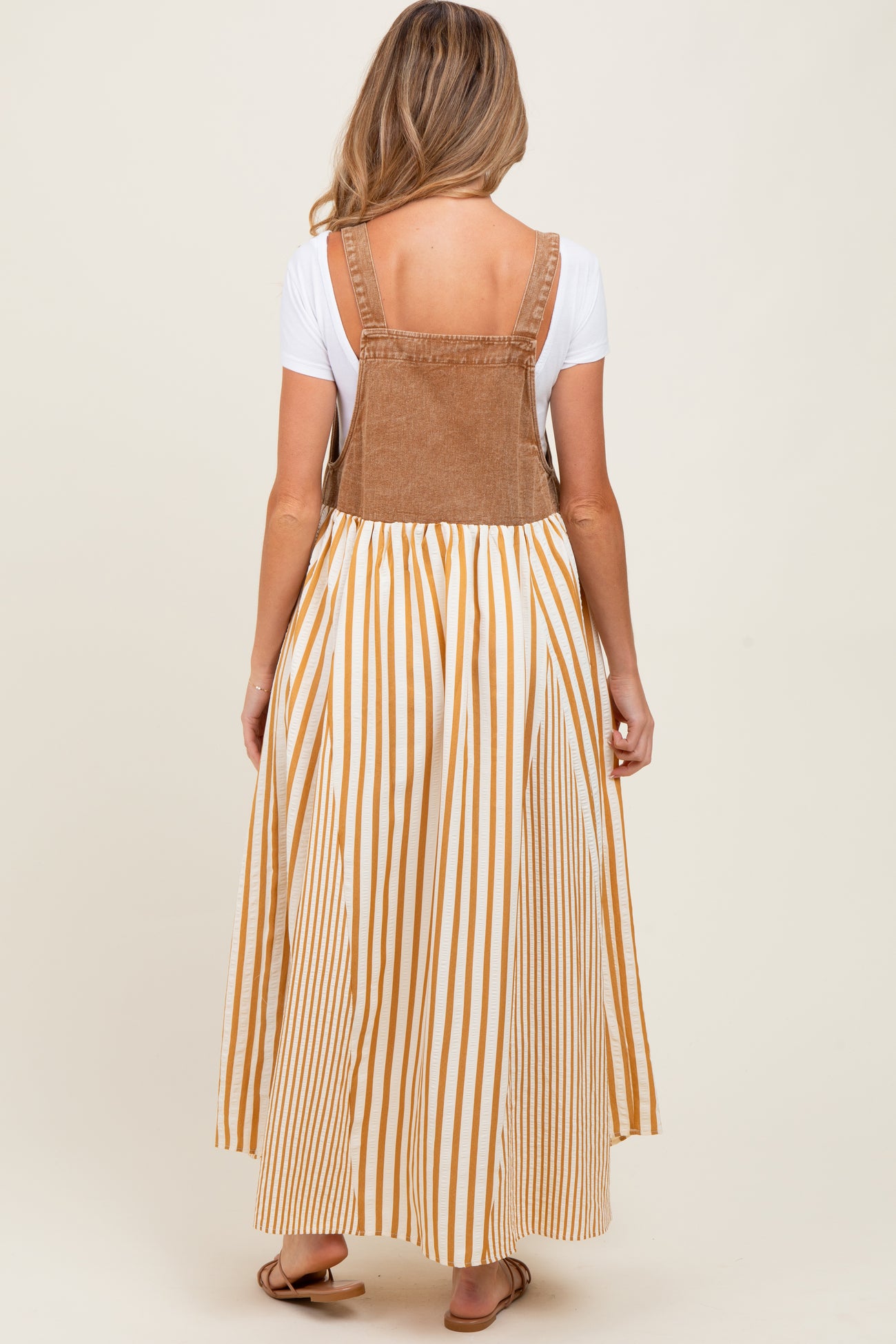 woman wearing a brown corduroy maternity maxi dress with white and mustard stripes and a fitted bodice