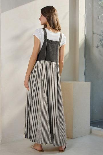 woman wearing a black and white striped maxi dress with a fitted top and flared skirt, showing the back view