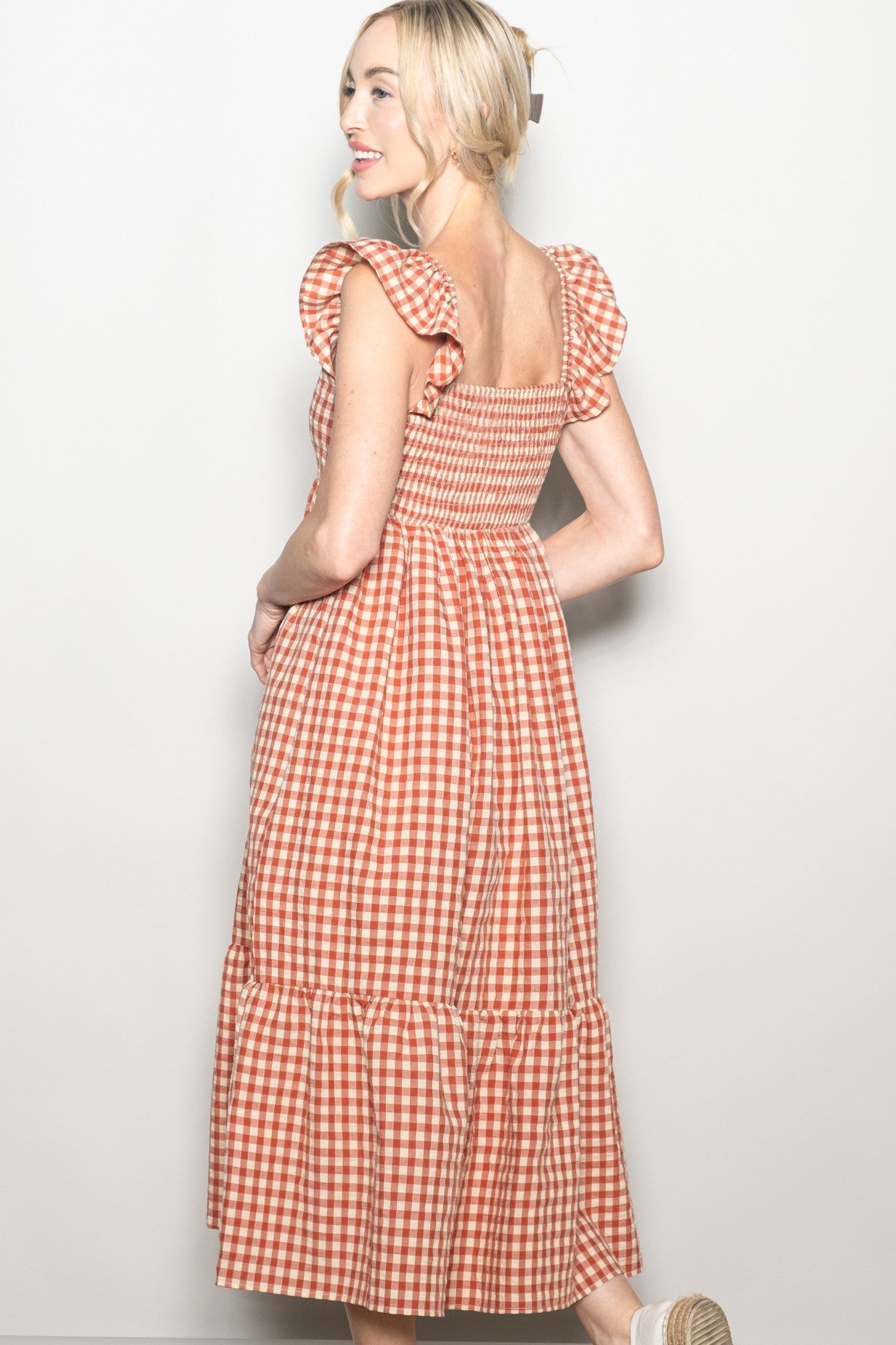 woman wearing a red and white gingham midi dress with ruffle sleeves and tiered skirt, seen from the back