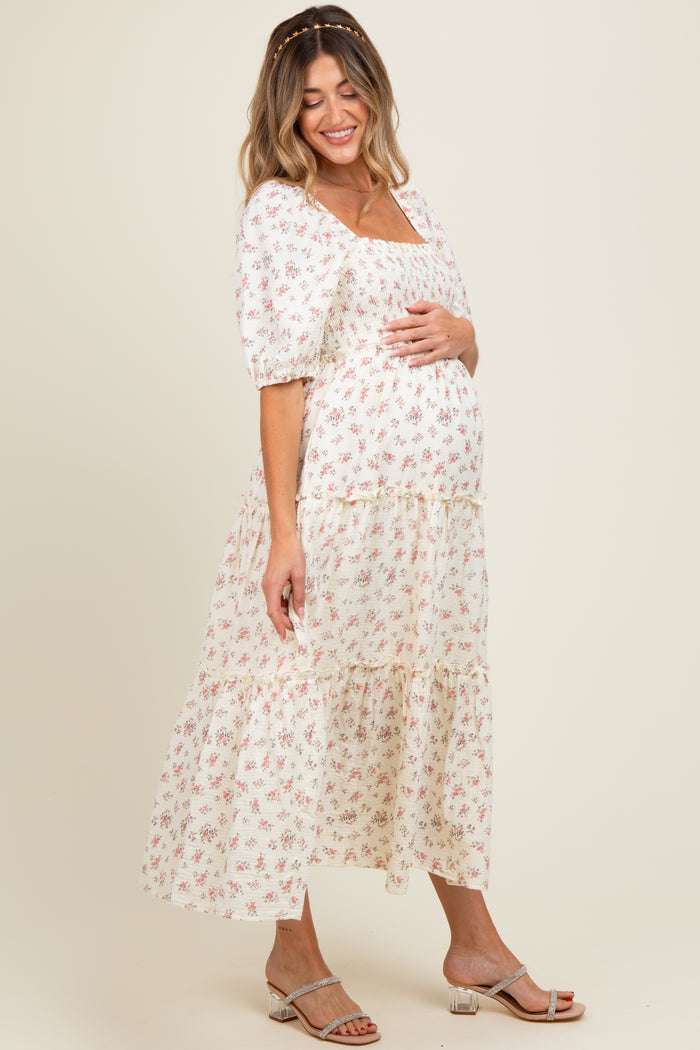 woman wearing a floral print maternity maxi dress with puff sleeves and holding her baby bump