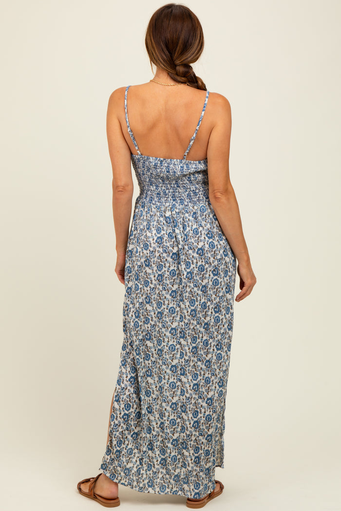 woman wearing a blue and white floral maxi dress with a smocked back and side slits, showing a back view