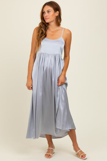 woman wearing a light blue satin maxi dress with spaghetti straps and a flowing skirt