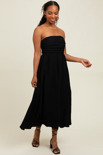 woman wearing a black strapless maxi dress with tiered pleats and a flowing silhouette