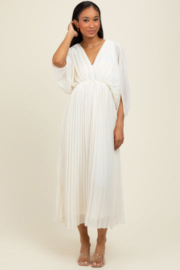 woman wearing a flowing white pleated midi dress with a deep v-neck and batwing sleeves