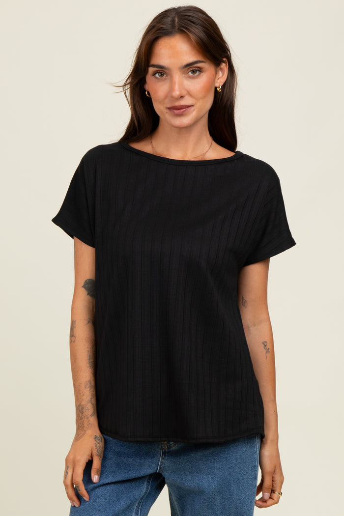woman wearing a black short sleeve ribbed top with a relaxed fit, standing in front of a neutral background