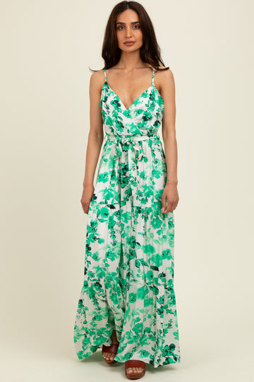 woman wearing a green floral maxi dress with thin straps and a tie waist detail