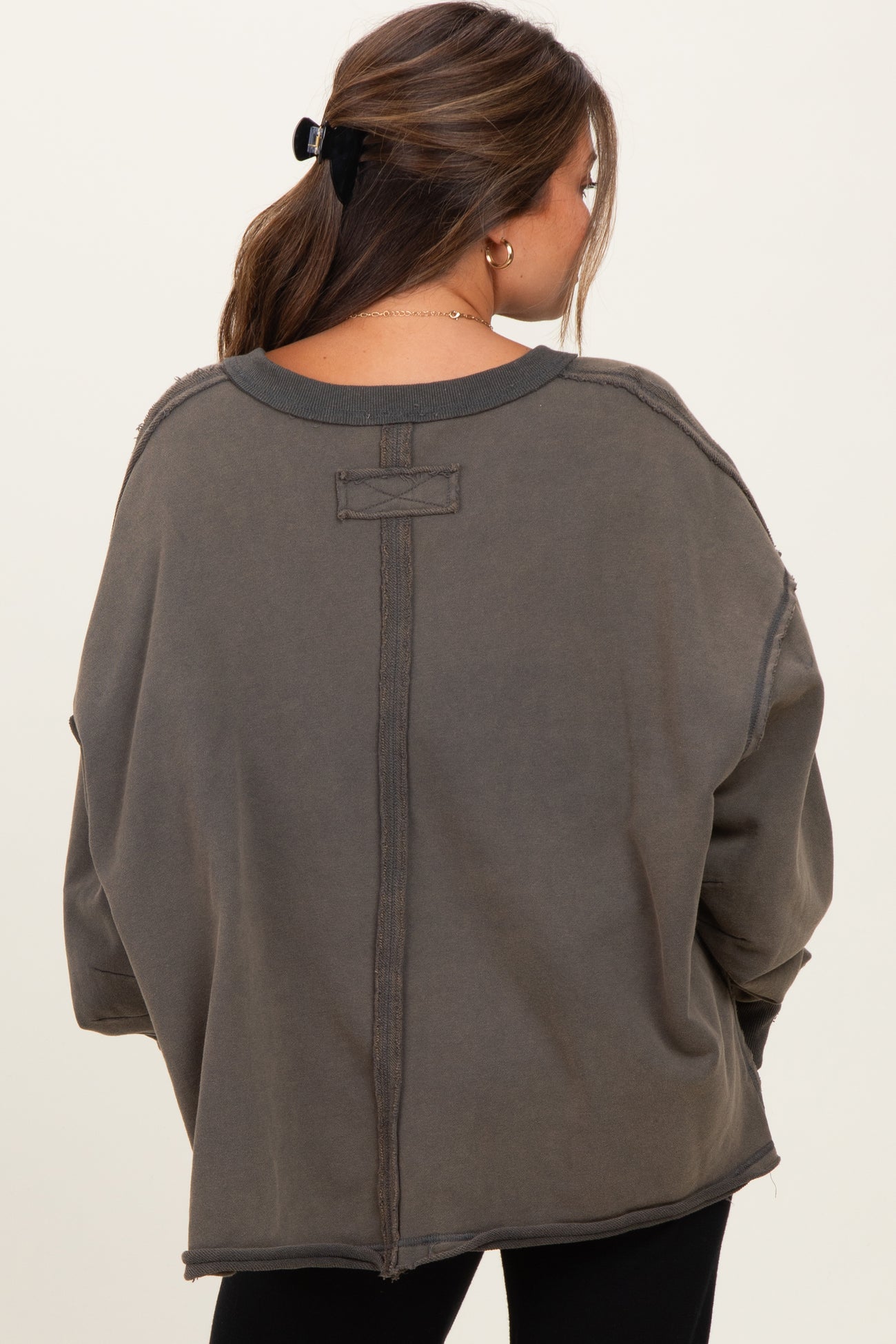 woman wearing a loose-fitting dark gray maternity sweatshirt with distressed details and a relaxed silhouette