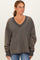 woman wearing a dark gray oversized v-neck sweatshirt with raw hem and long sleeves