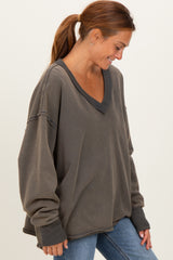 woman wearing a loose-fitting dark gray v-neck sweatshirt with distressed details and long sleeves
