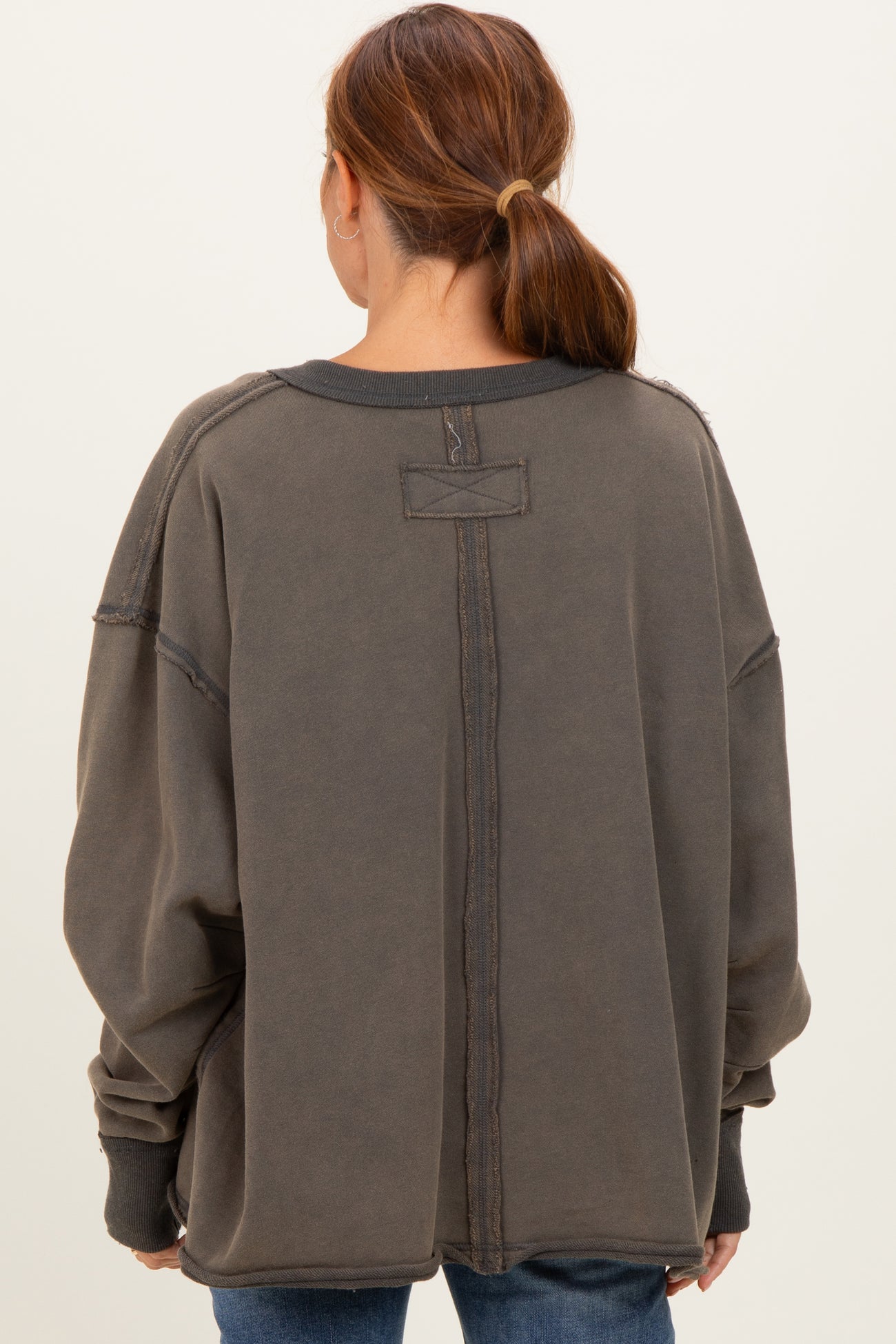 woman wearing an oversized charcoal gray fleece sweatshirt with a back seam detail