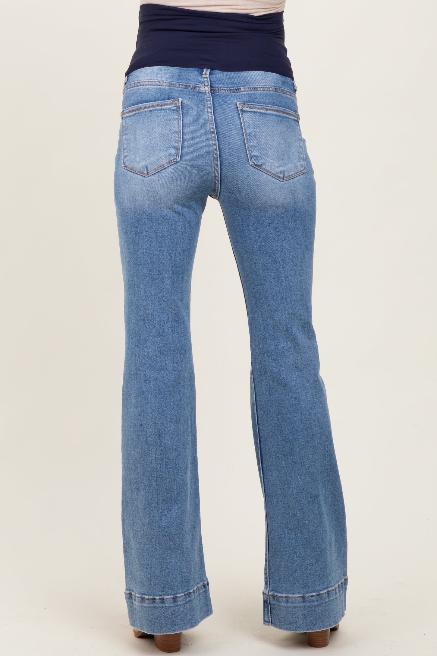 woman wearing light blue maternity flared jeans with a stretchy dark waistband, showcasing the back view