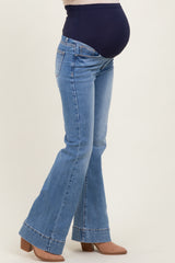 woman wearing a pair of blue flared maternity jeans with a navy over-the-bump panel and visible baby bump
