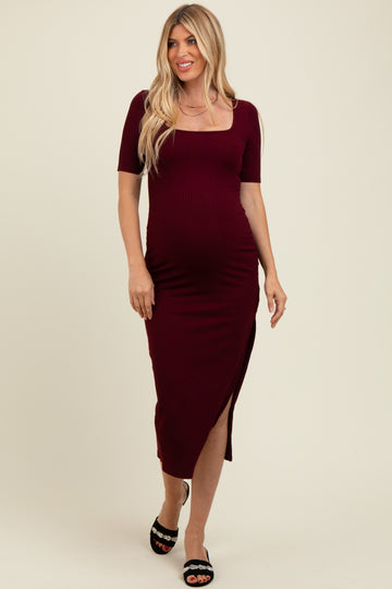 woman wearing a burgundy ribbed maternity dress with a square neckline and side slit, showing her baby bump