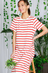 woman wearing a red and white striped oversized t-shirt dress while sitting and holding a small bouquet of flowers