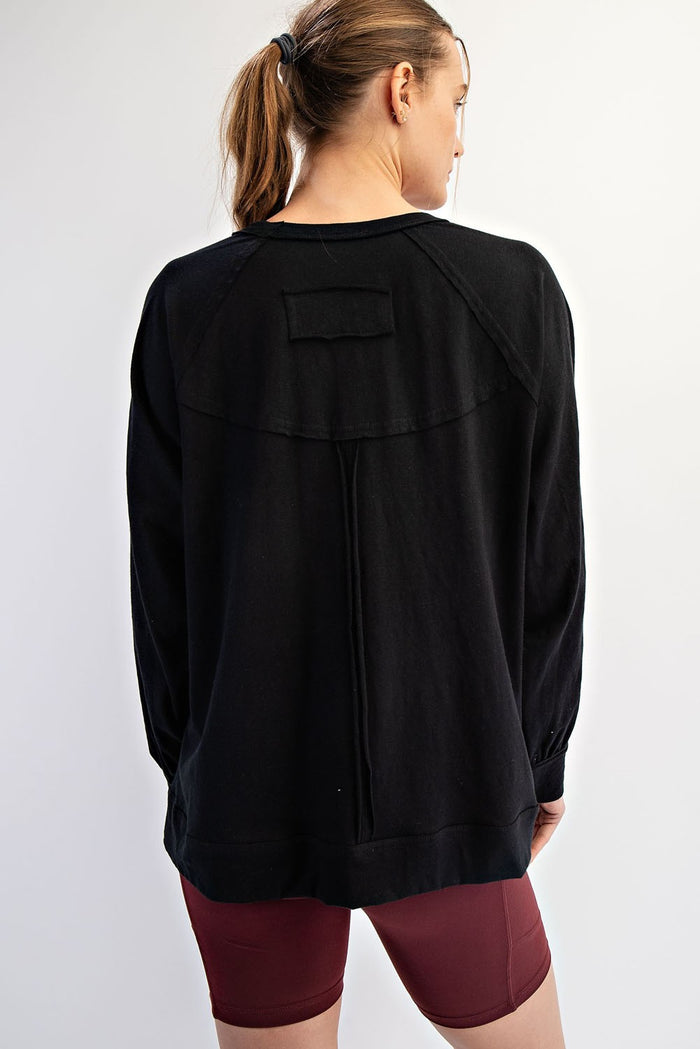 woman wearing a black oversized sweatshirt with a yoke detail and long sleeves, showing the back view