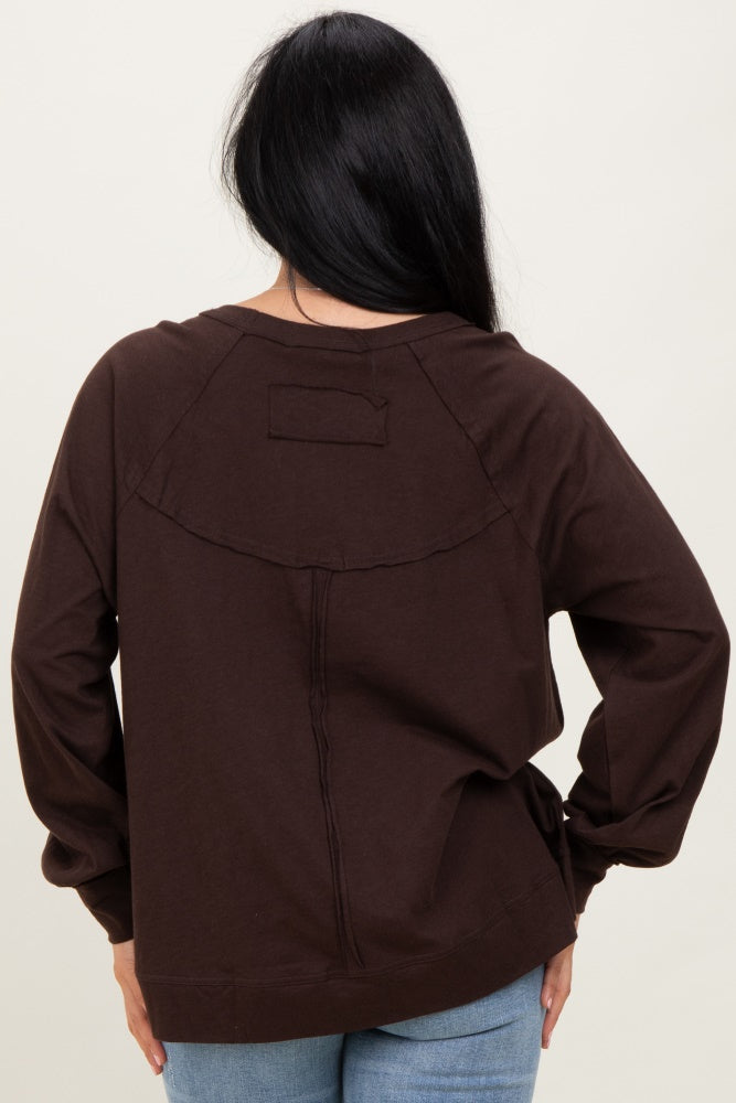 woman wearing a dark brown long sleeve top with a relaxed fit and back yoke seam detail