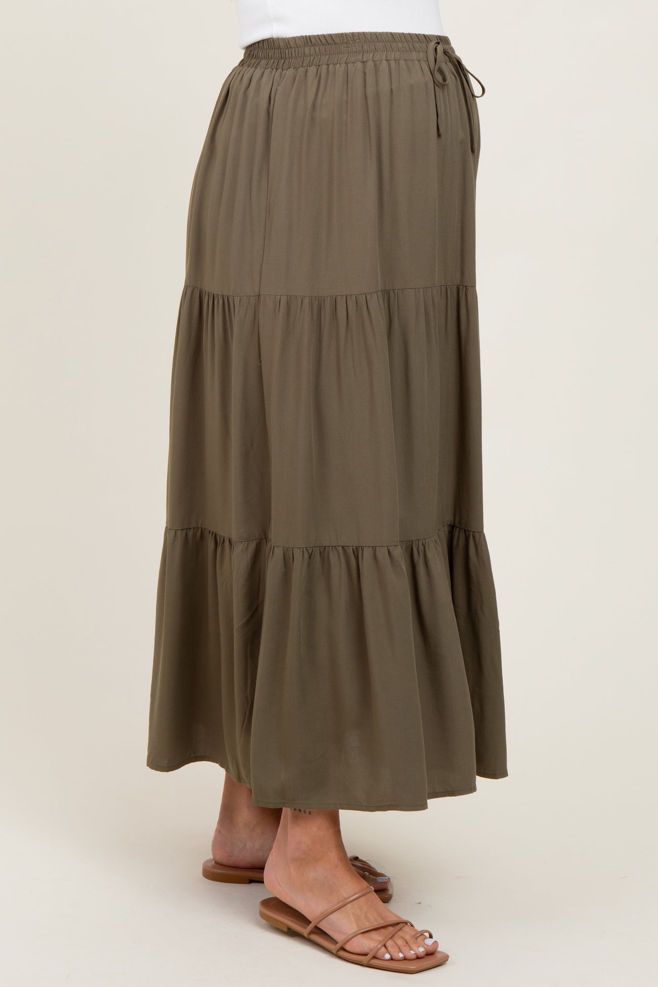 woman wearing a green tiered maternity maxi skirt with an elastic waistband and drawstring detail