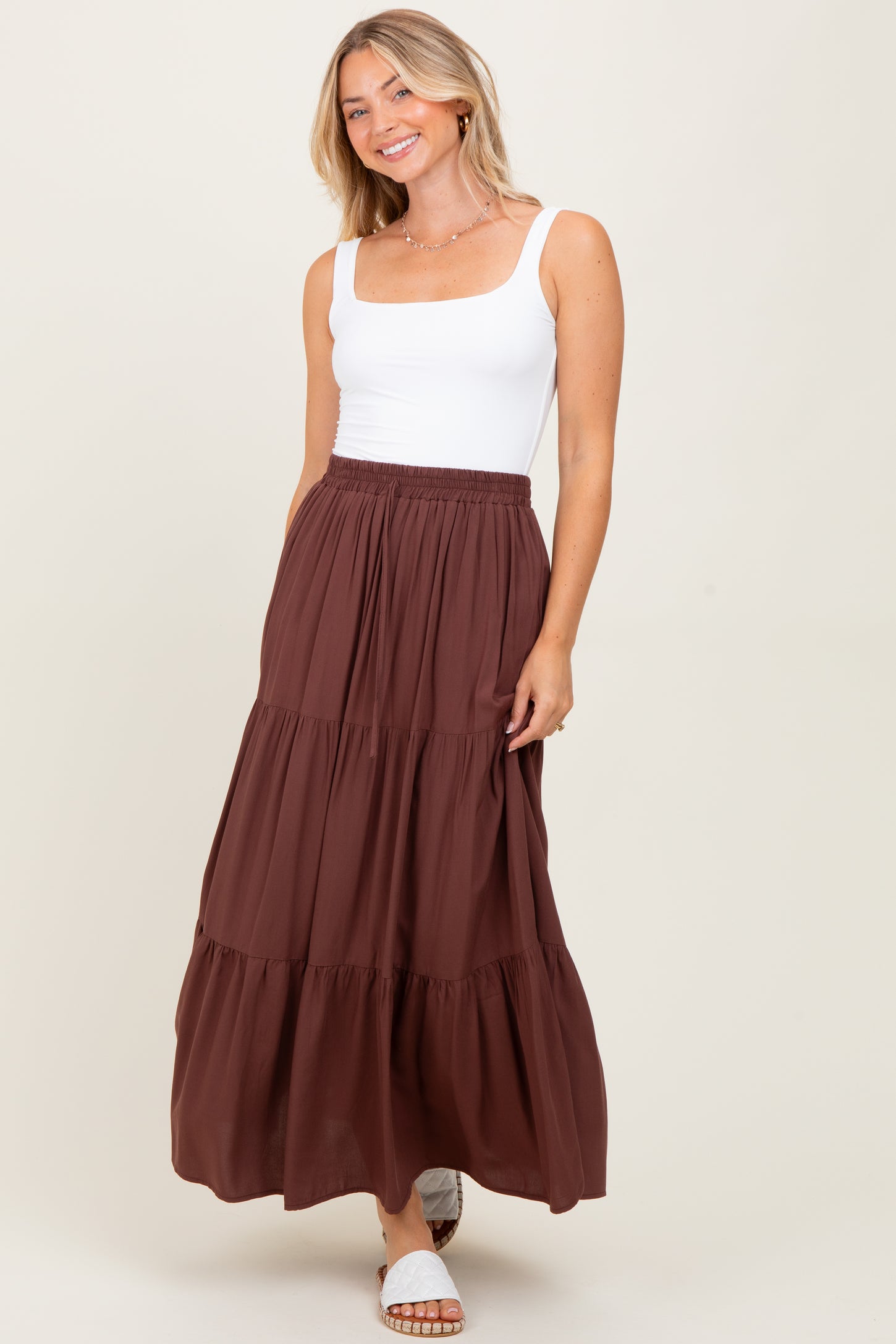 woman wearing a white square neck tank top and a brown tiered maxi skirt with a smocked waistband