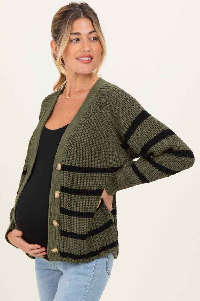 woman wearing a green and black striped maternity cardigan with buttons, holding her baby bump