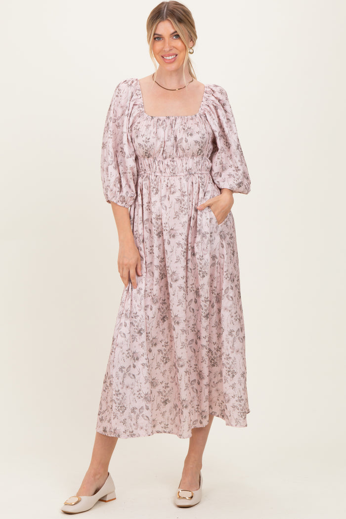woman wearing a pink floral midi dress with puff sleeves and side pockets