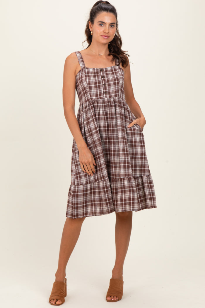 woman wearing a brown plaid midi dress with adjustable straps and pockets