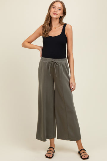 woman wearing a black tank top and olive green maternity wide-leg pants with an elastic waistband