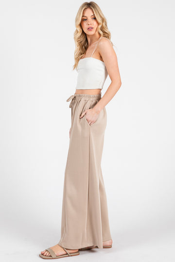 woman wearing a white ribbed crop top and beige wide-leg pants with an elastic waistband and side pockets