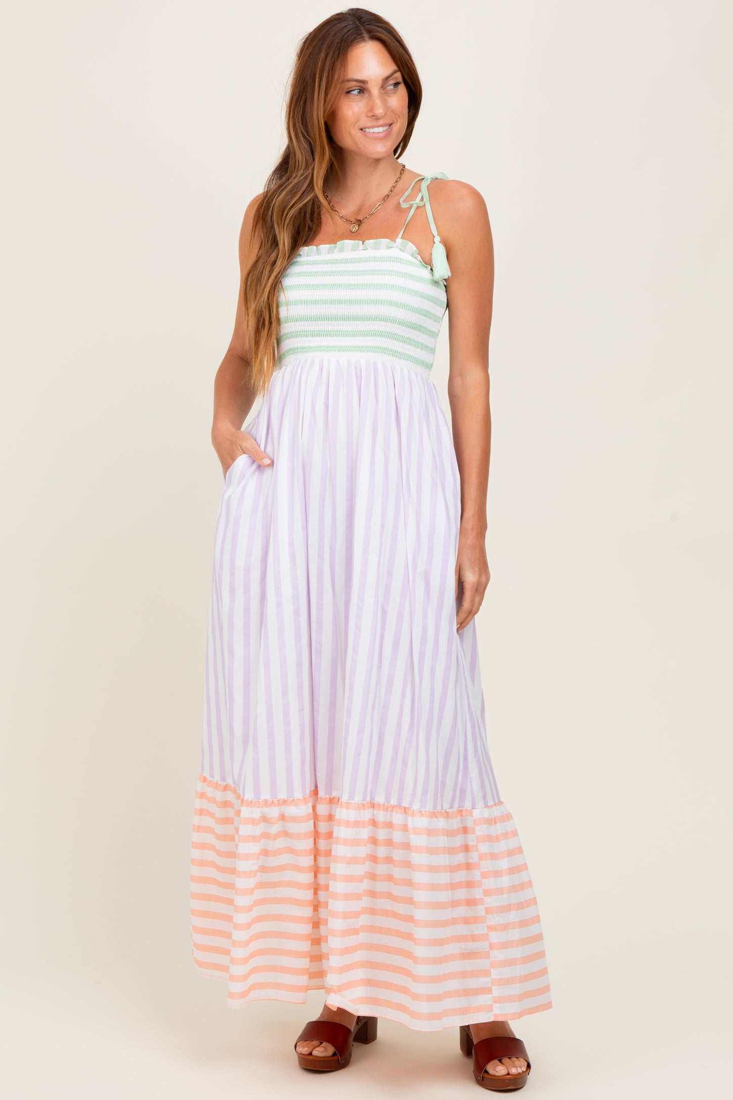woman wearing a striped maxi dress with a smocked bodice and tiered skirt in pastel colors