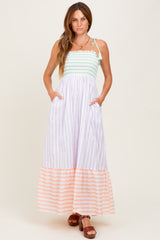 woman wearing a striped maxi dress with a mint top and peach bottom, featuring pockets and adjustable straps