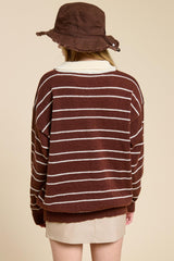 woman wearing a brown and white striped oversized sweater with a wide neckline and a brown bucket hat