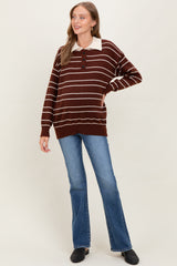 woman wearing a brown and cream striped maternity sweater with a collared neckline, paired with flared jeans