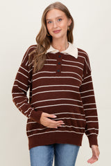 woman wearing a brown and cream striped maternity sweater with a collared neckline and holding her baby bump