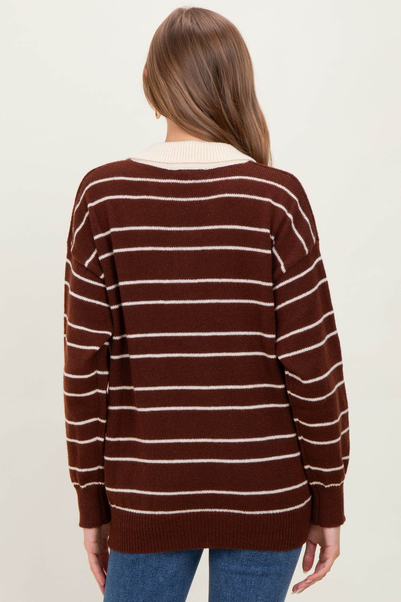 woman wearing a brown and white striped maternity sweater, showing the back view with a loose fit and ribbed cuffs