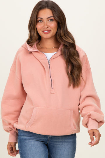 woman wearing a dusty rose maternity sweatshirt with a half-zip and front pocket, paired with blue jeans