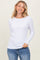 woman wearing a white long sleeve ribbed top and blue jeans, smiling at the camera
