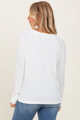 woman wearing a white long sleeve ribbed top, viewed from the back, paired with blue jeans